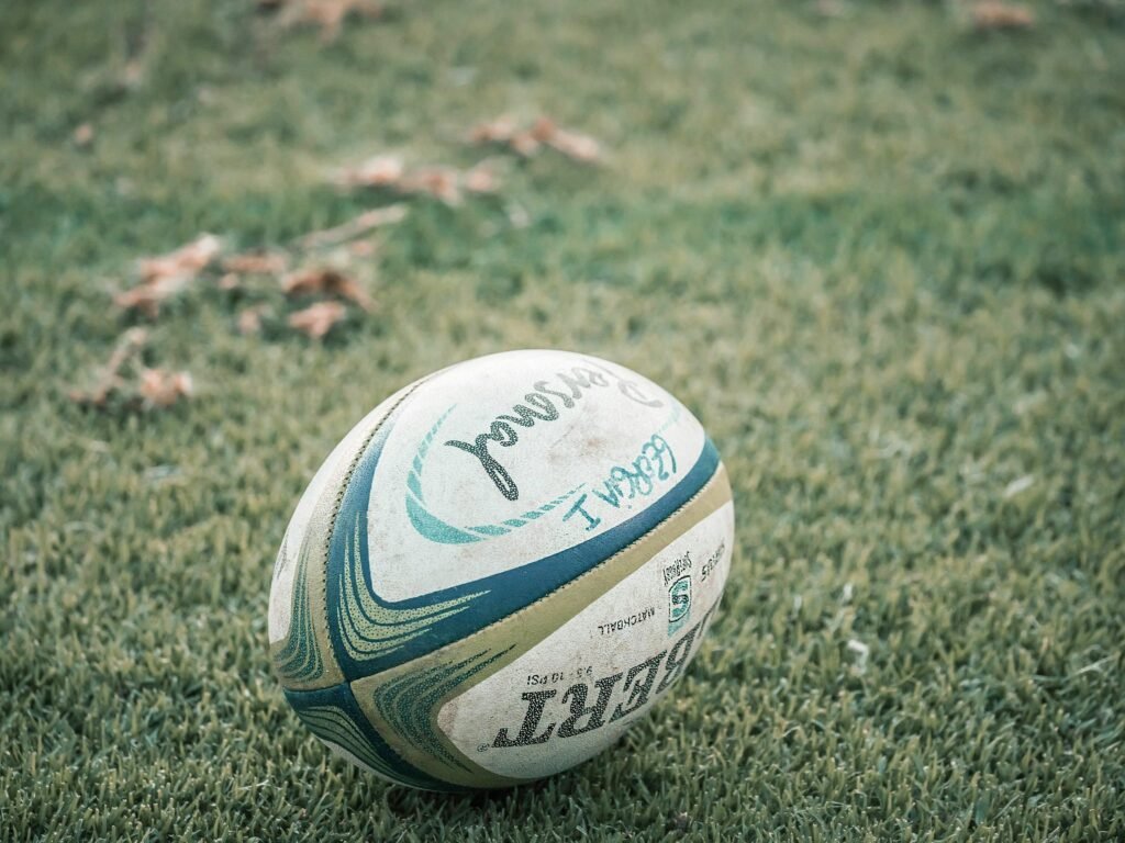 A close-up shot of a rugby ball resting on a grass field, ideal for sports theme.